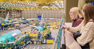 Tour guests overlook the balcony from inside the Boeing Everett Factory. The Boeing 777 assembly line is in motion on the factory floor below.