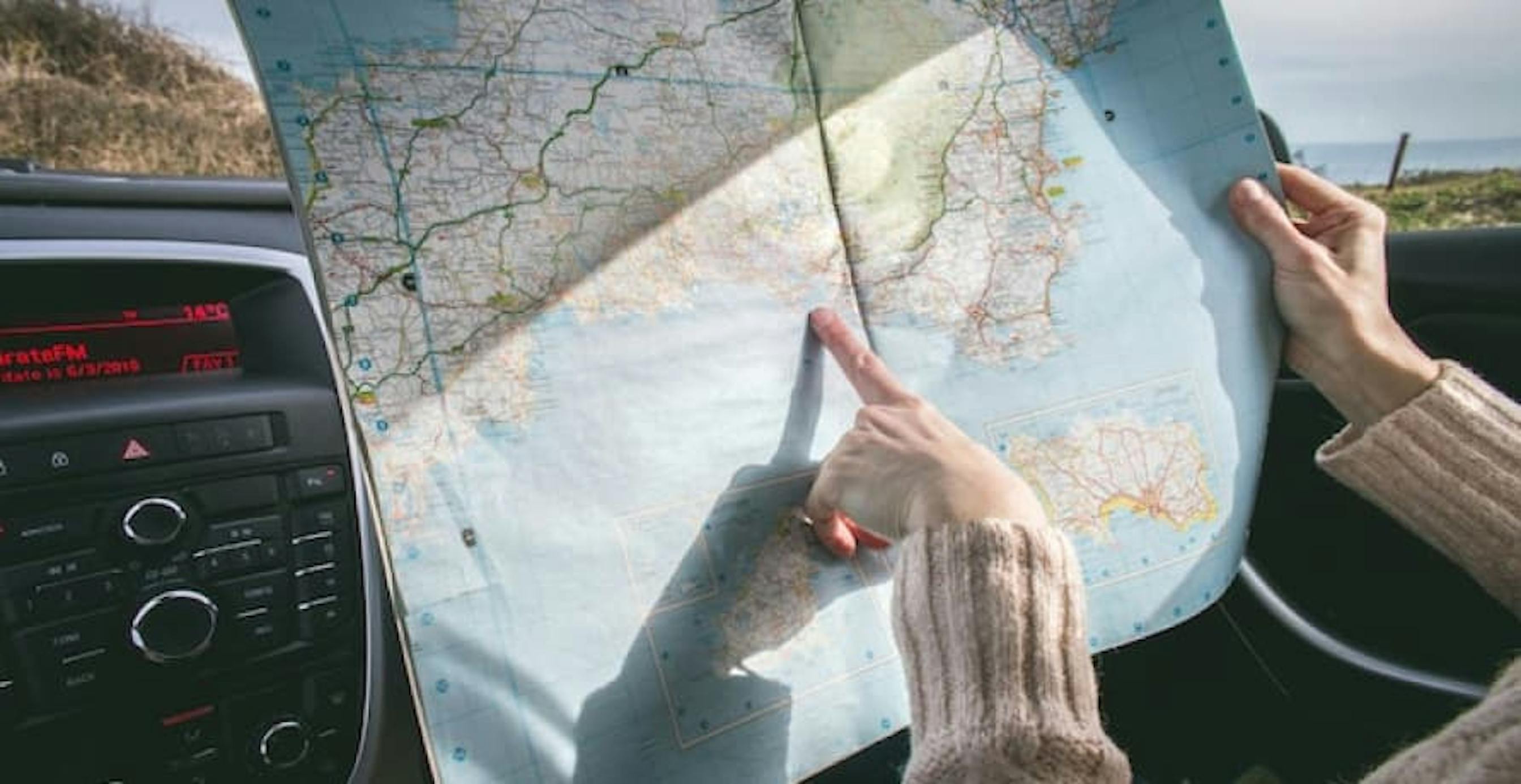 person with map in car pointing to destination