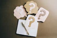 Image of four question marks and a notebook and a pen