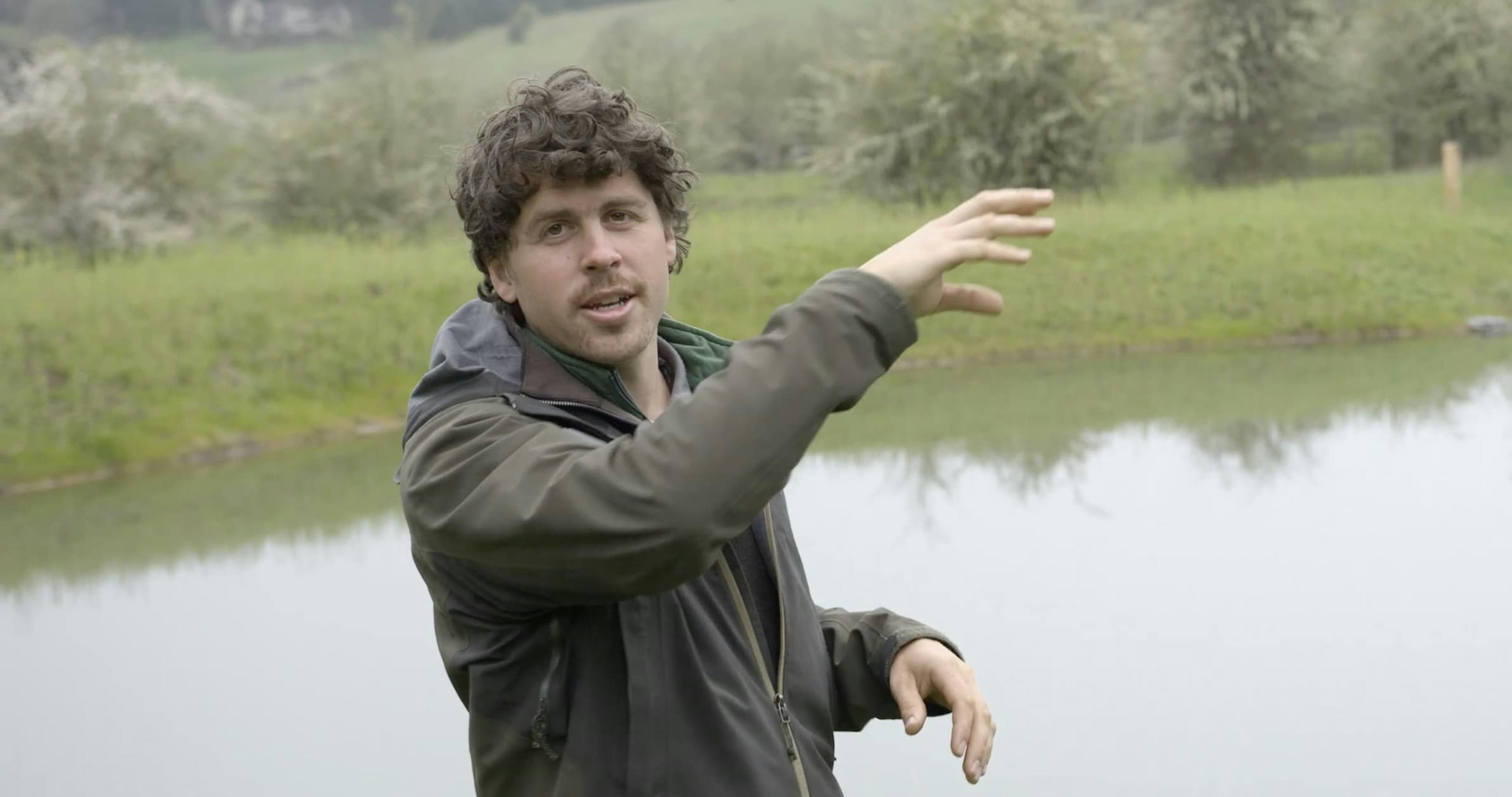 Zach explaining a water cycle restoration concept in front of a water retention body
