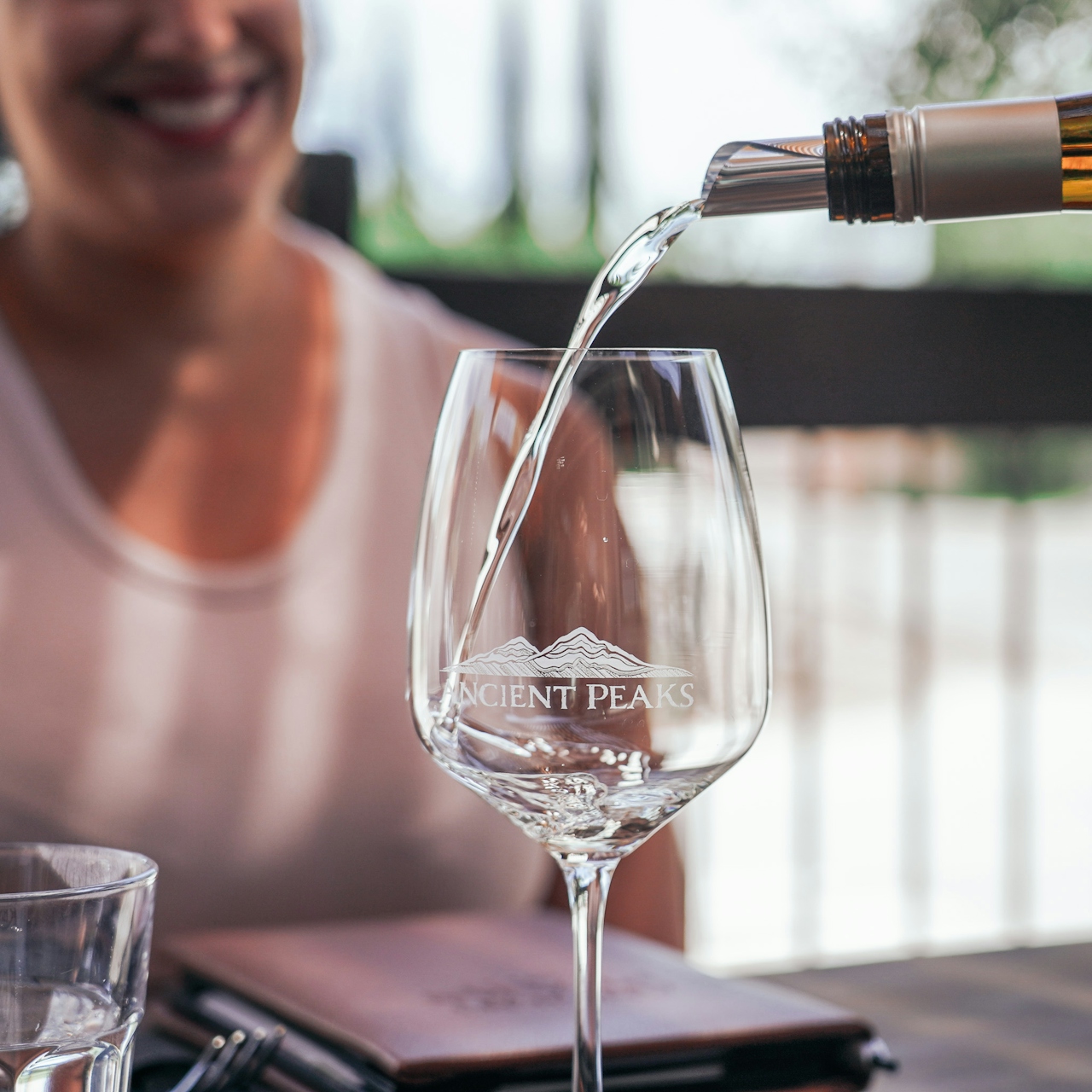 A woman smiles as a white wine is poured for her to taste at Ancient Peaks Winery in Paso Robles 